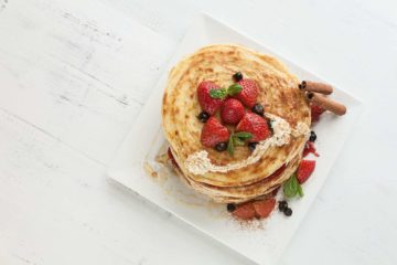 White Plate Full Of Pancakes With Raspberries Strawberries Blueberries And Honey